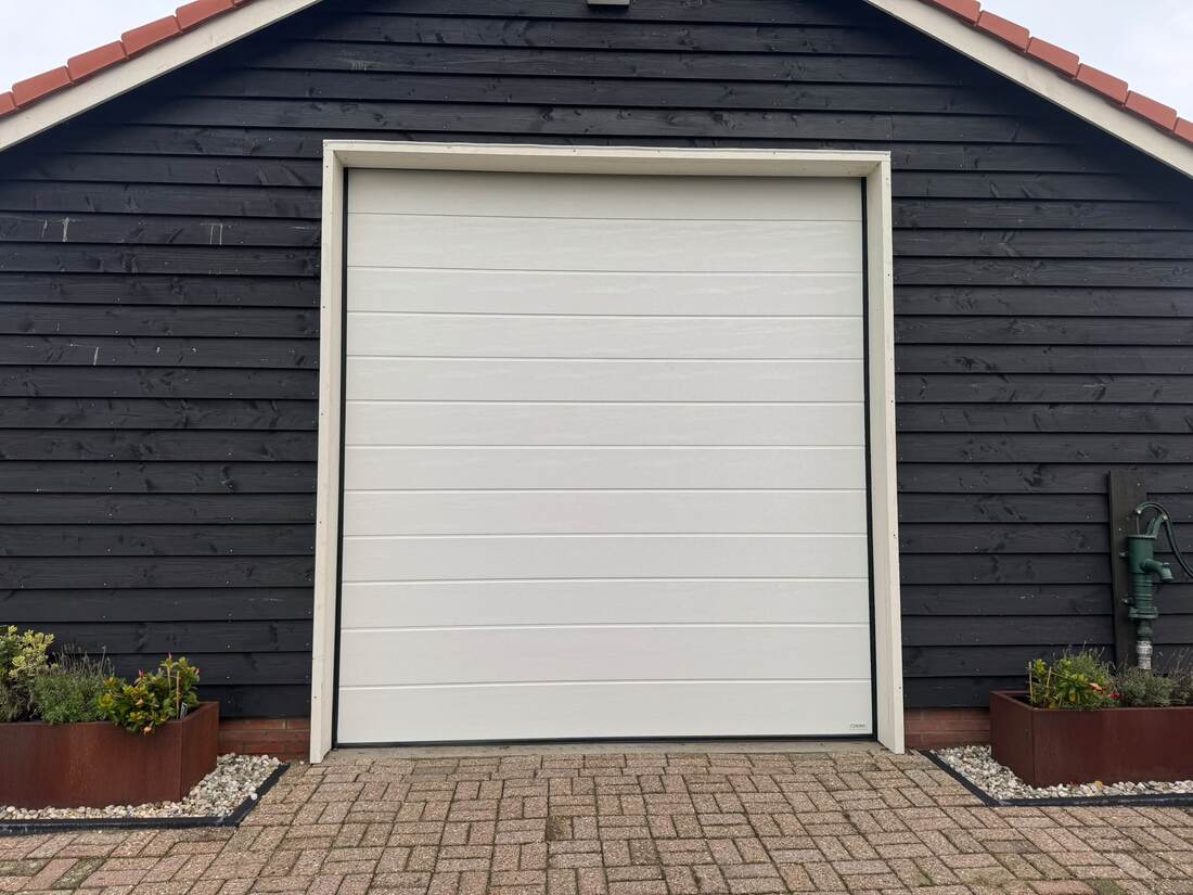 Grote witte bedrijfsdeur in zwart geklede loods